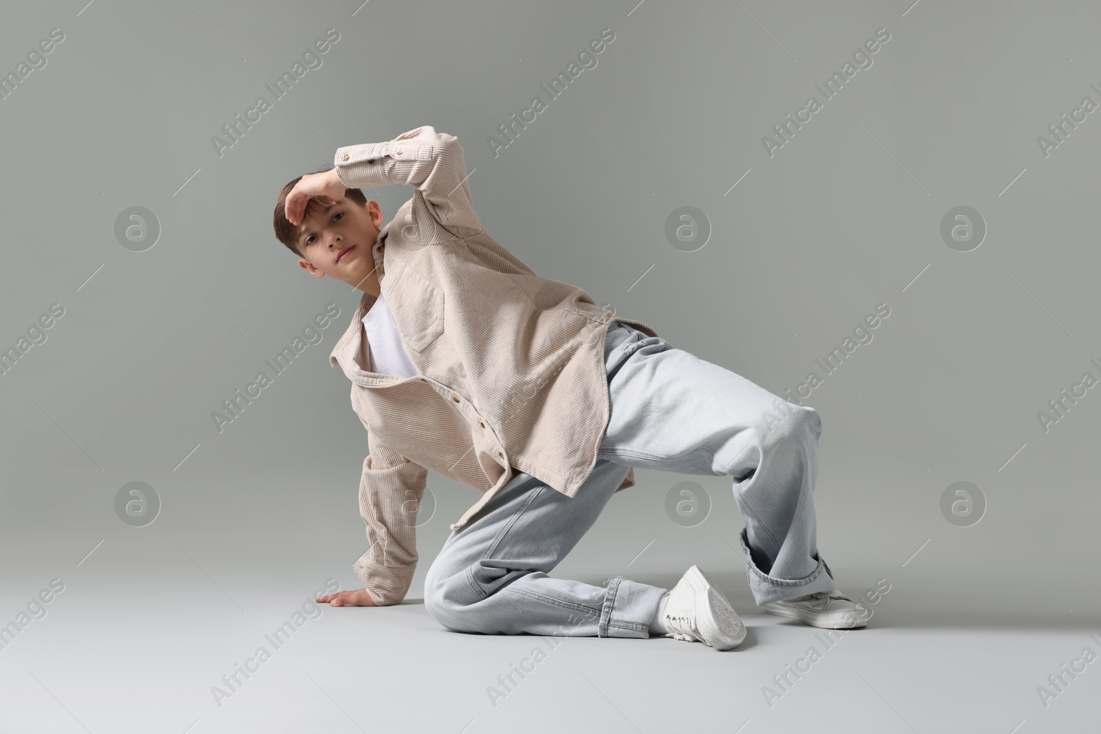 Boy in stylish clothes dancing on light grey background Photo of Boy in stylish clothes dancing on light grey background
