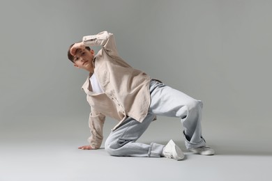 Photo of Boy in stylish clothes dancing on light grey background