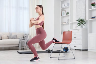 Photo of Beautiful woman exercising with chair at home