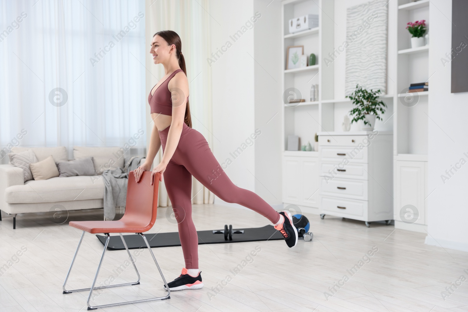 Beautiful woman exercising with chair at home Photo of Beautiful woman exercising with chair at home