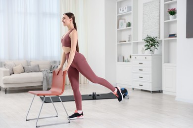 Photo of Beautiful woman exercising with chair at home