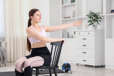 Photo of Beautiful woman stretching on chair at home