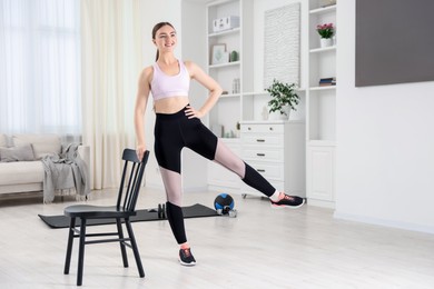 Photo of Beautiful woman exercising with chair at home
