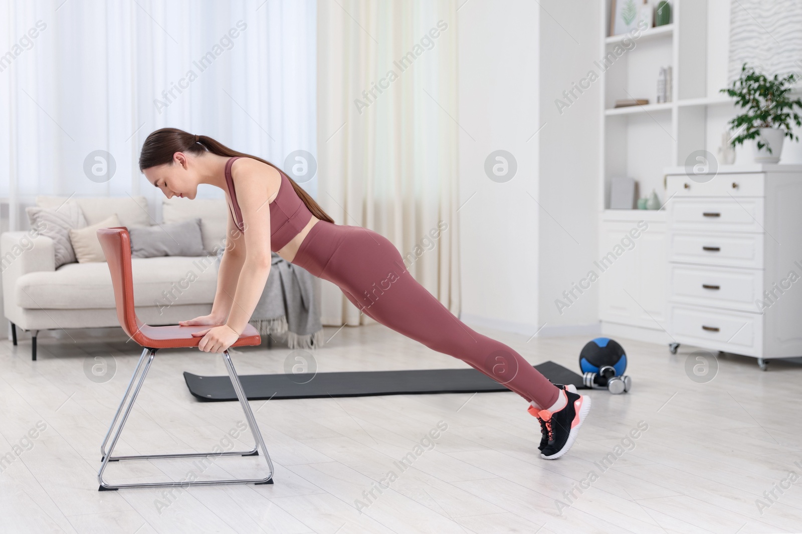 Beautiful woman exercising with chair at home Photo of Beautiful woman exercising with chair at home
