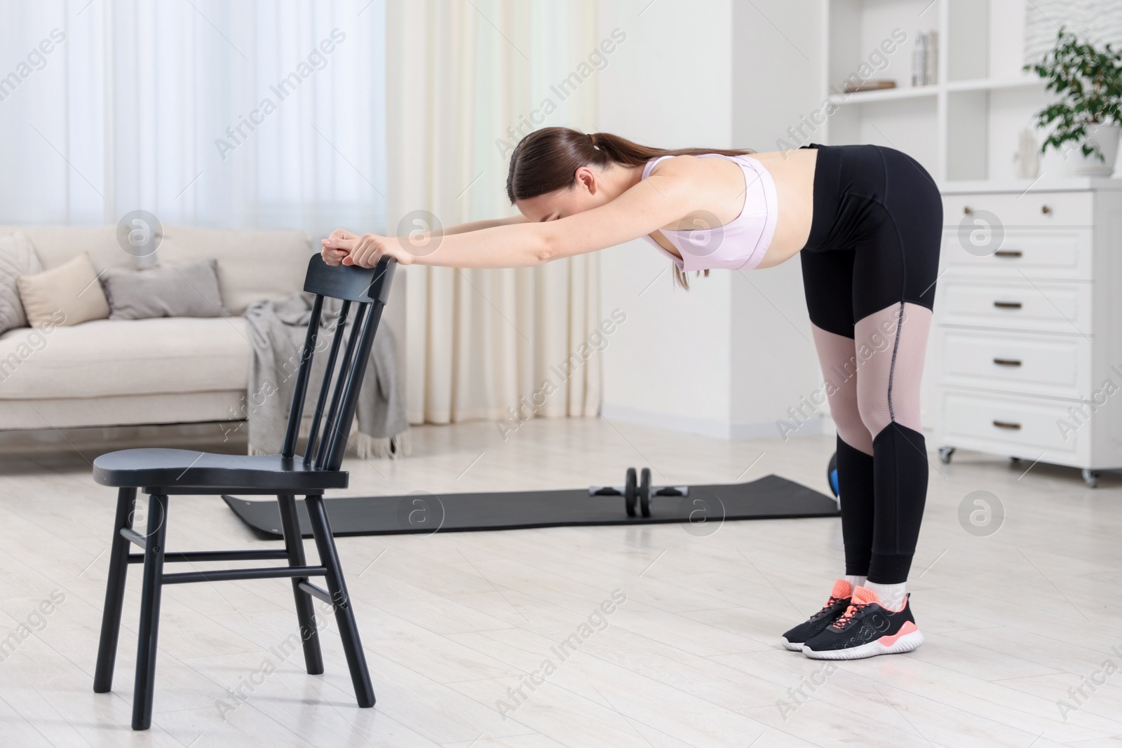 Young woman exercising with chair at home Photo of Young woman exercising with chair at home