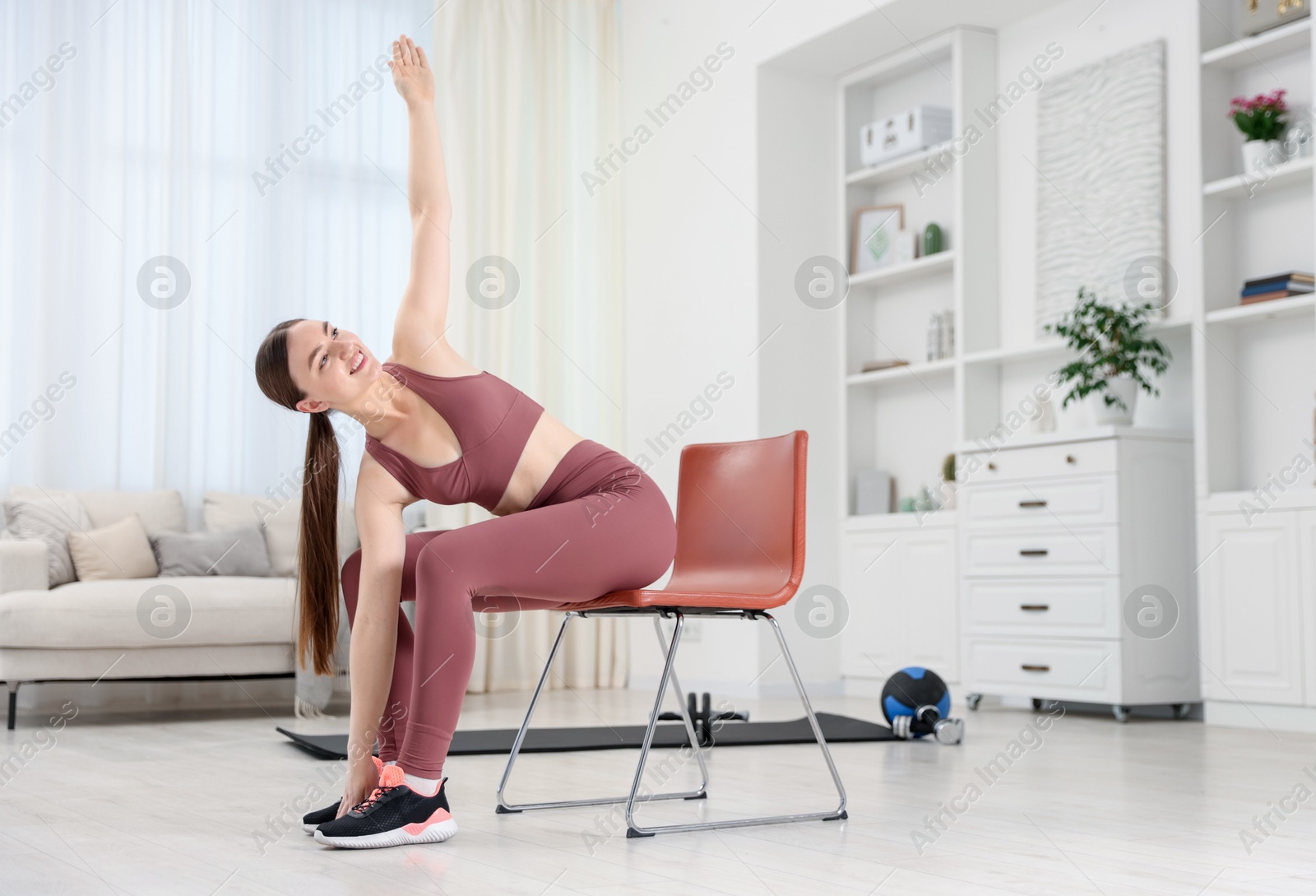 Beautiful woman stretching on chair at home, space for text Photo of Beautiful woman stretching on chair at home, space for text