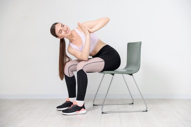 Photo of Beautiful woman stretching on chair at home