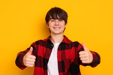 Photo of Teenage boy showing thumbs up on orange background