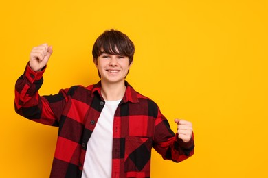 Photo of Portrait of teenage boy on orange background, space for text