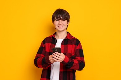 Photo of Teenage boy with smartphone on orange background