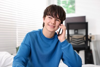 Photo of Teenage boy talking on smartphone at home