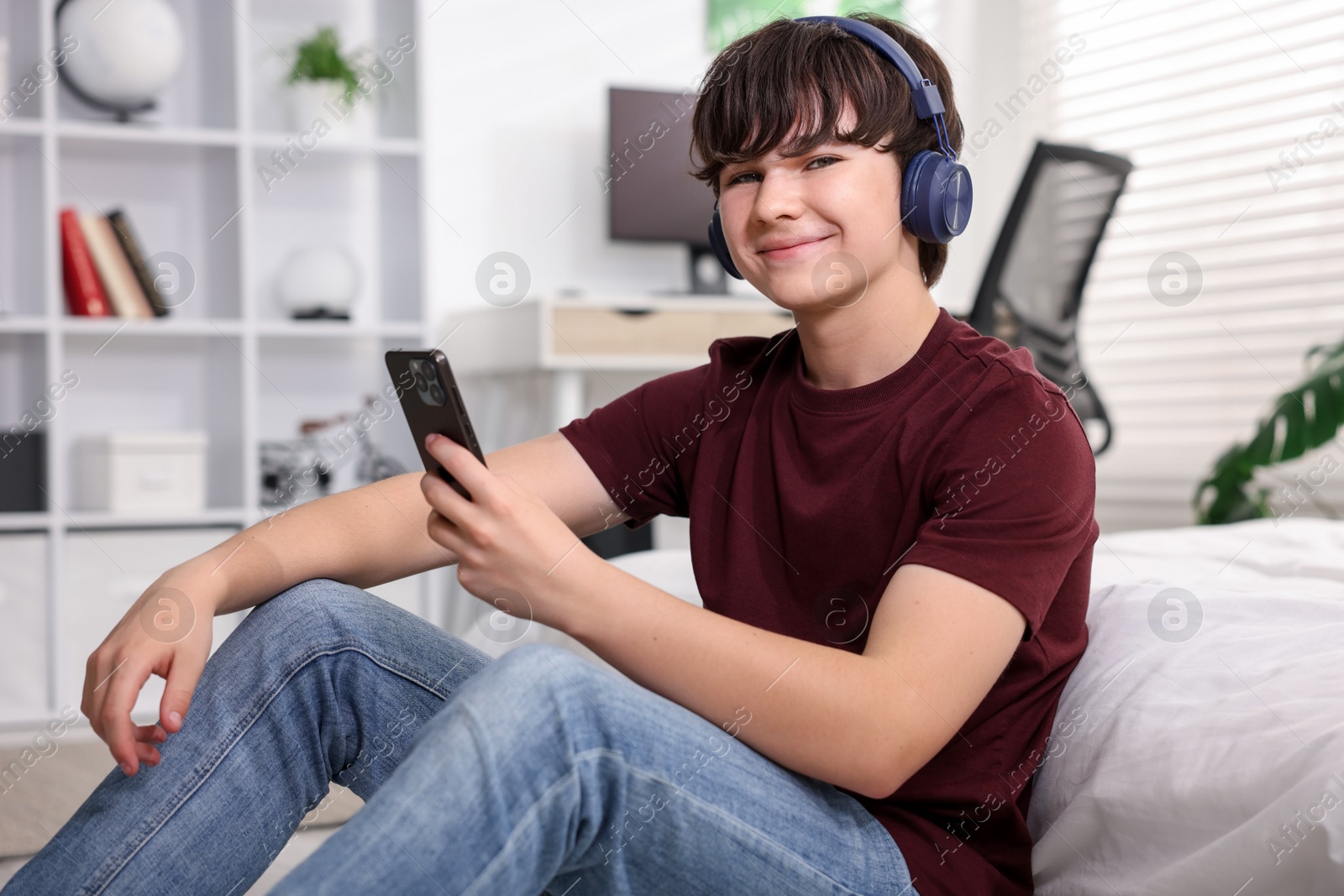 Teenage boy in headphones using smartphone at home Photo of Teenage boy in headphones using smartphone at home