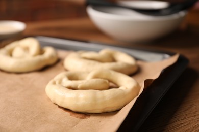 Photo of Uncooked pretzels on wooden table, closeup view