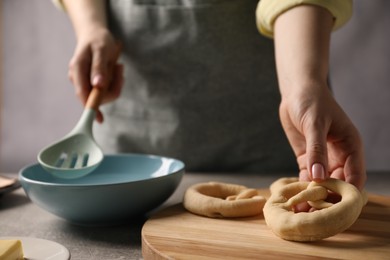 Photo of Woman taking uncooked pretzel at grey table, closeup