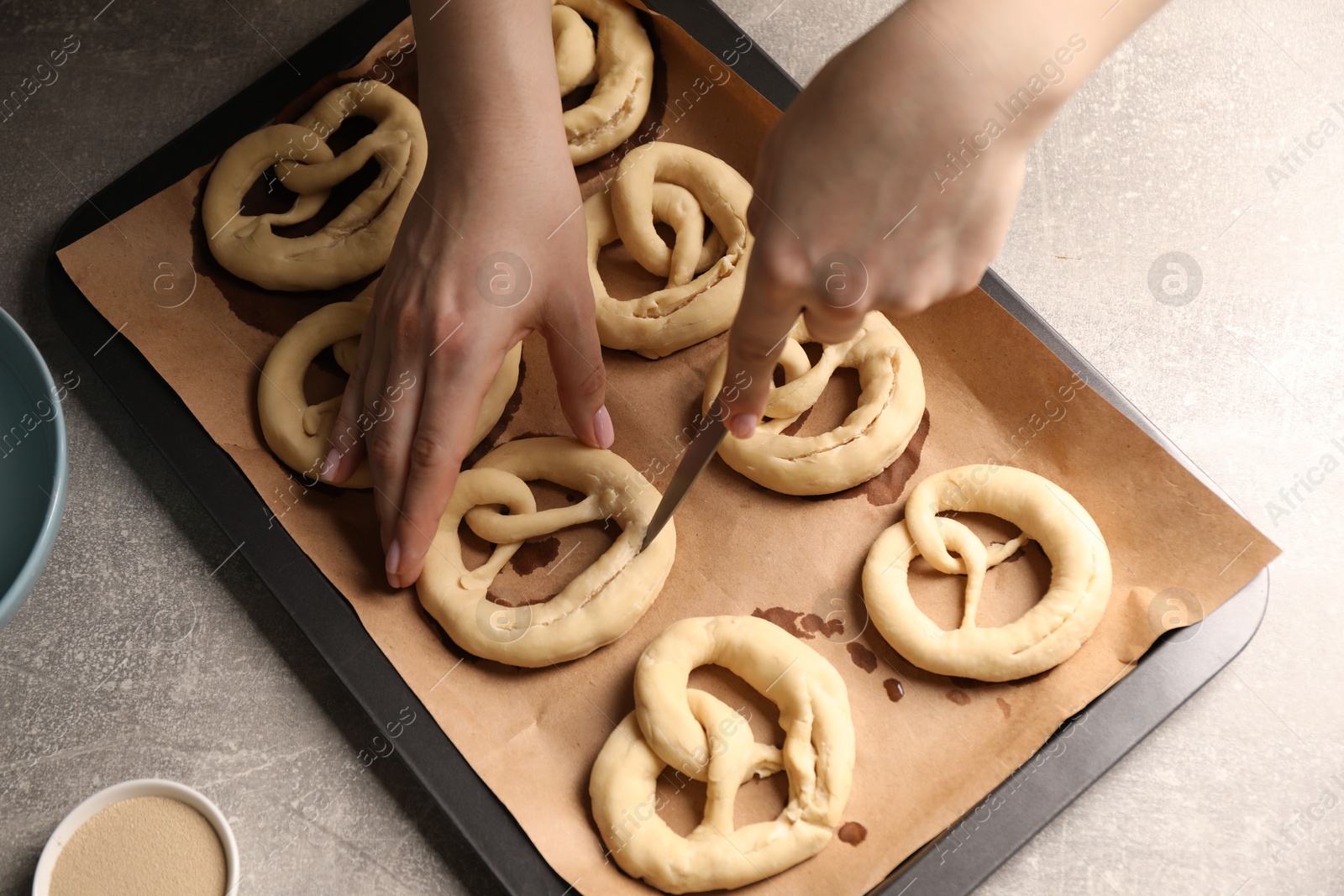 Woman cutting uncooked pretzel at grey table, above view Photo of Woman cutting uncooked pretzel at grey table, above view