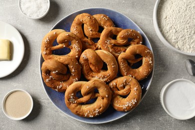 Photo of Tasty pretzels and ingredients on grey table, flat lay