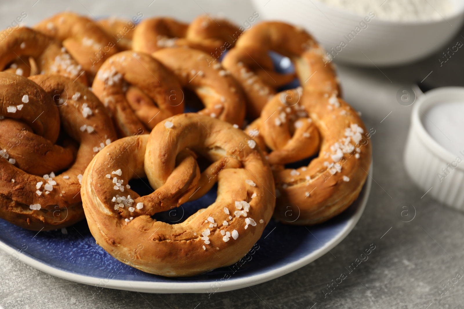 Tasty pretzels with salt on grey table, closeup Photo of Tasty pretzels with salt on grey table, closeup