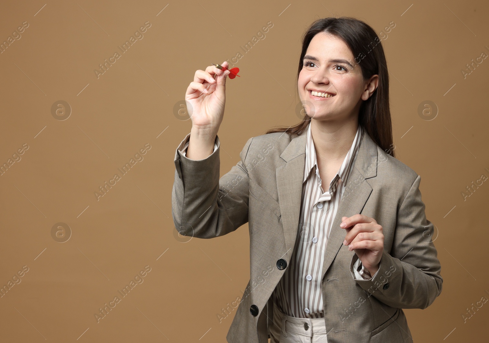 Targeting. Smiling businesswoman with dart aiming on beige background Photo of Targeting. Smiling businesswoman with dart aiming on beige background