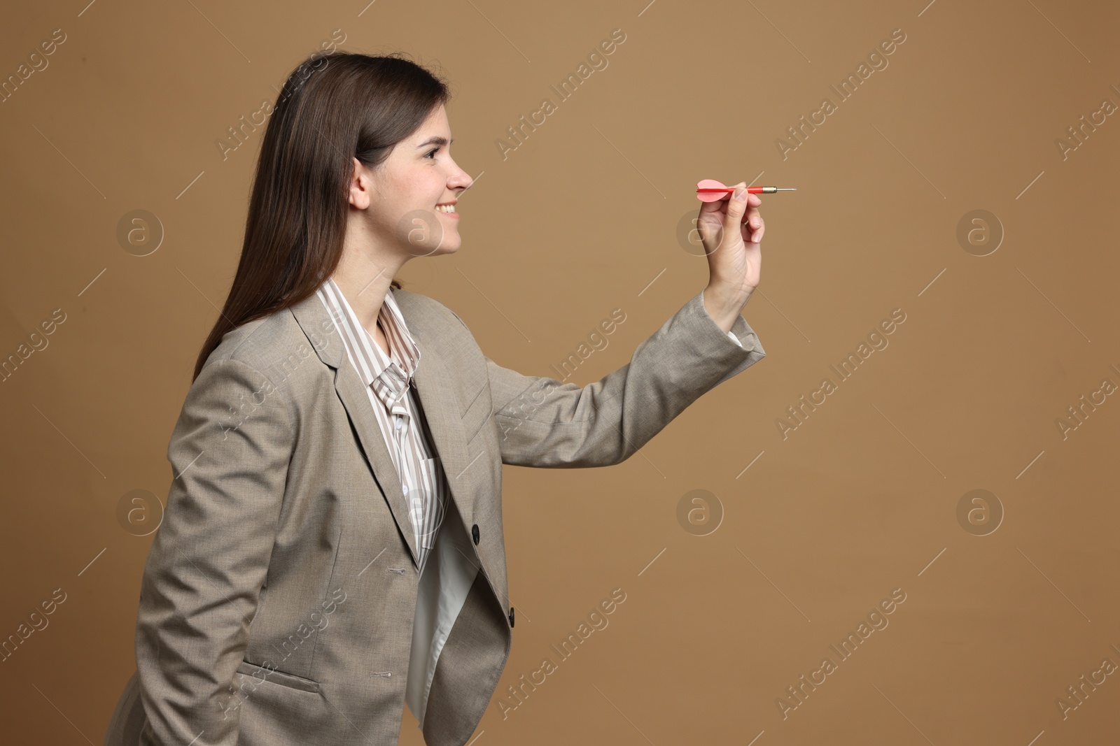 Targeting. Smiling businesswoman with dart aiming on beige background Photo of Targeting. Smiling businesswoman with dart aiming on beige background