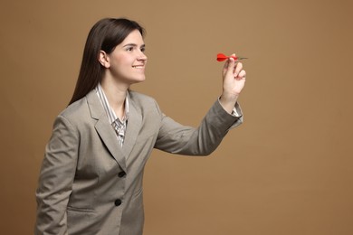Photo of Targeting. Smiling businesswoman with dart aiming on beige background