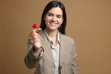 Photo of Targeting. Smiling businesswoman with dart on beige background, selective focus