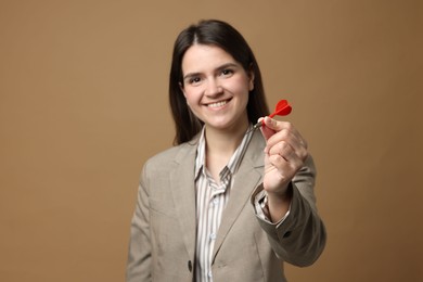 Photo of Targeting. Smiling businesswoman with dart on beige background, selective focus