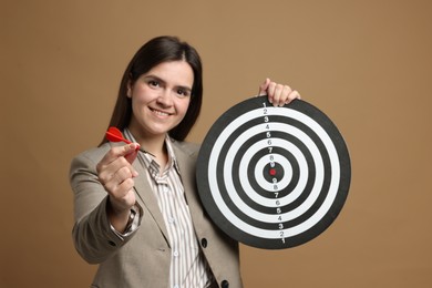 Photo of Targeting. Smiling businesswoman with dart board and arrow on beige background