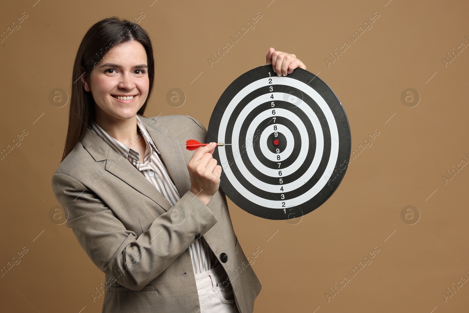 Targeting. Smiling businesswoman with dart board and arrow on beige background Photo of Targeting. Smiling businesswoman with dart board and arrow on beige background