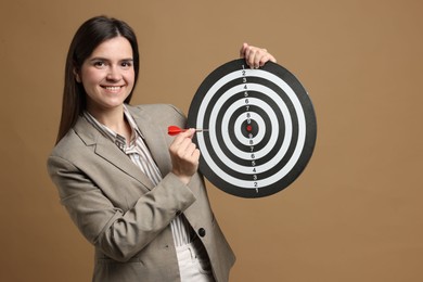 Photo of Targeting. Smiling businesswoman with dart board and arrow on beige background