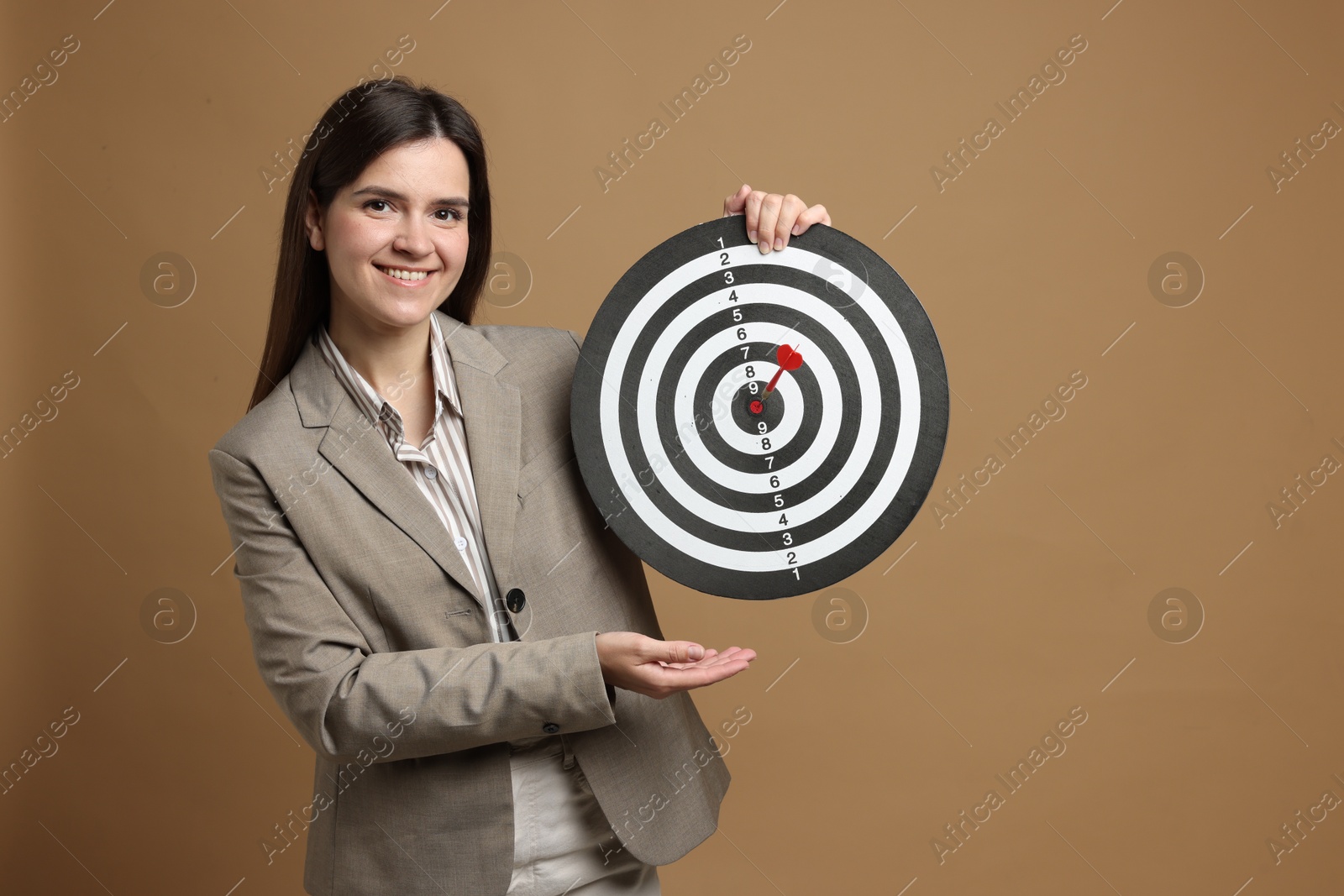 Targeting. Smiling businesswoman with dart board and arrow on beige background Photo of Targeting. Smiling businesswoman with dart board and arrow on beige background