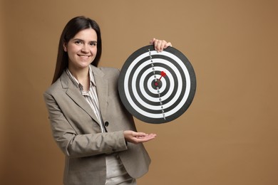 Photo of Targeting. Smiling businesswoman with dart board and arrow on beige background