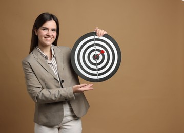 Photo of Targeting. Smiling businesswoman with dart board and arrow on beige background. Space for text