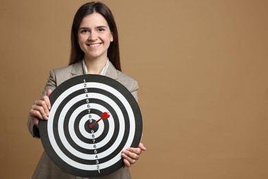 Photo of Targeting. Smiling businesswoman with dart board and arrow on beige background. Space for text