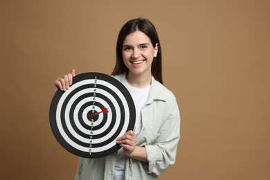 Photo of Targeting. Smiling woman with dart board and arrow on beige background