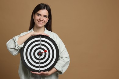 Photo of Targeting. Smiling woman with dart board and arrow on beige background. Space for text
