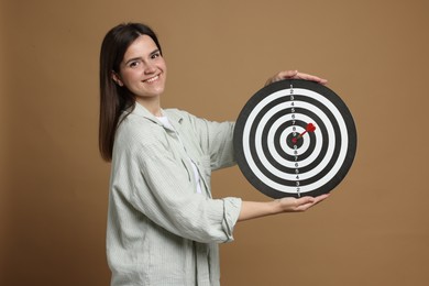 Photo of Targeting. Smiling woman with dart board and arrow on beige background