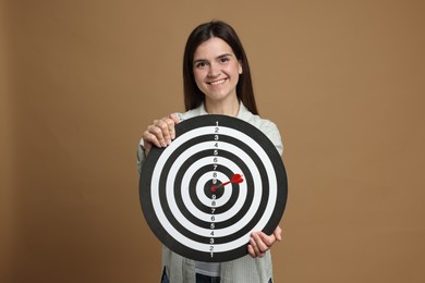 Photo of Targeting. Smiling woman with dart board and arrow on beige background