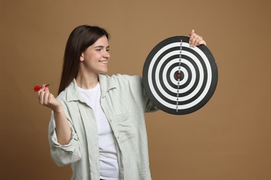 Photo of Targeting. Smiling woman with dart board and arrow on beige background