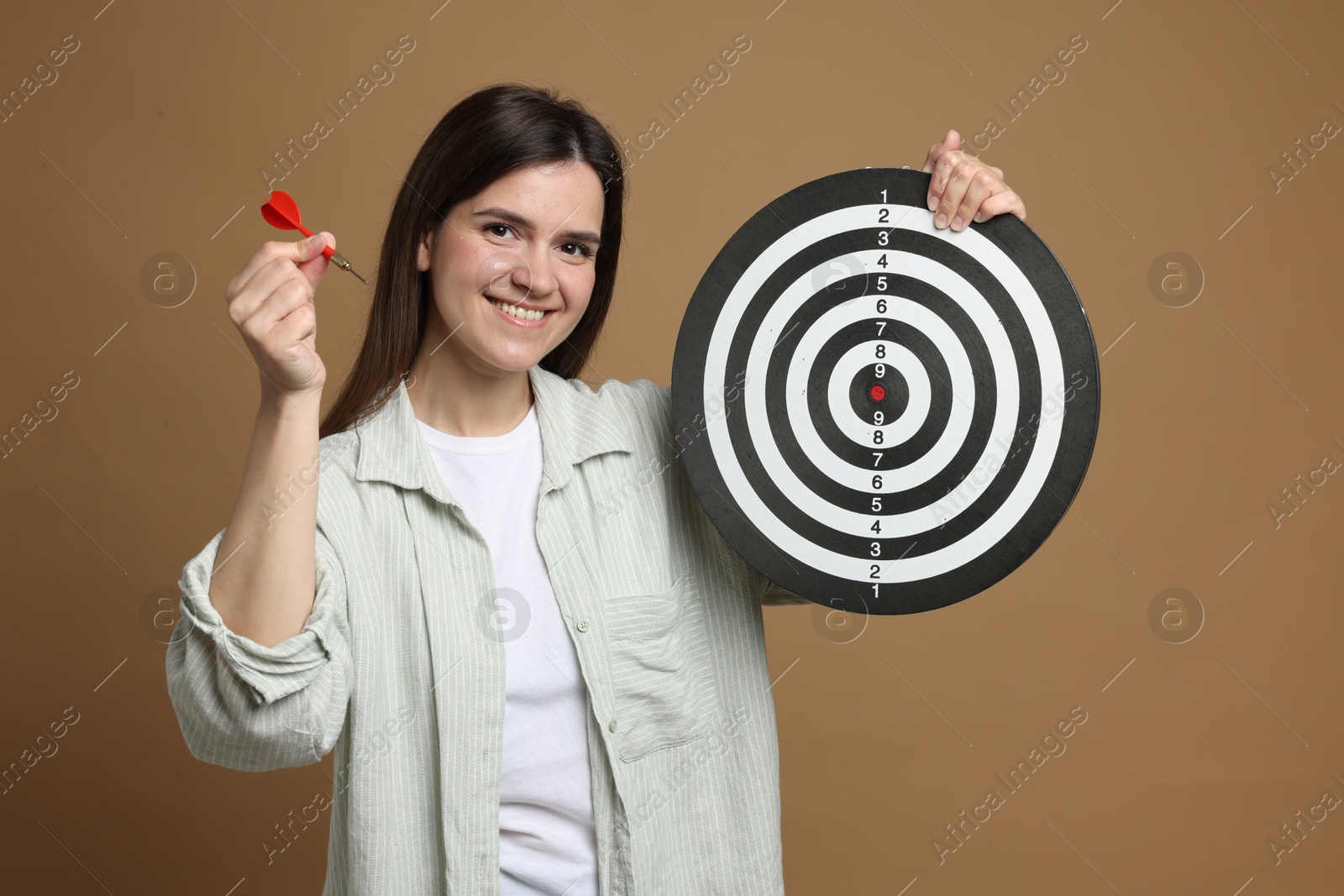 Targeting. Smiling woman with dart board and arrow on beige background Photo of Targeting. Smiling woman with dart board and arrow on beige background