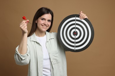 Photo of Targeting. Smiling woman with dart board and arrow on beige background
