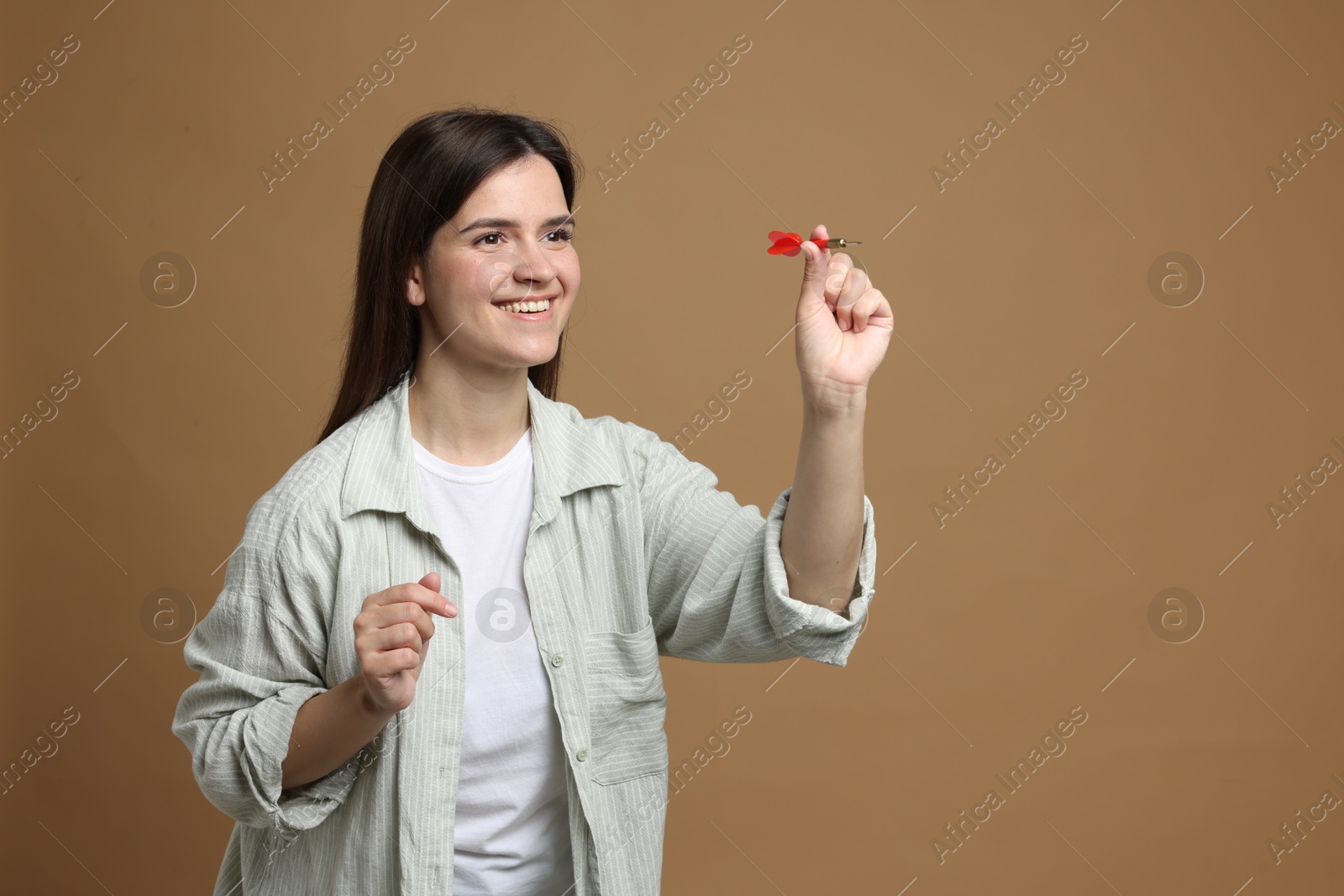 Targeting. Smiling woman with dart aiming on beige background Photo of Targeting. Smiling woman with dart aiming on beige background