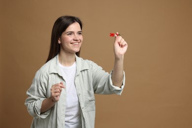Photo of Targeting. Smiling woman with dart aiming on beige background