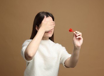 Photo of Targeting. Businesswoman with dart covering eyes on beige background