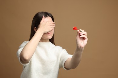 Photo of Targeting. Businesswoman with dart covering eyes on beige background