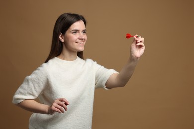 Photo of Targeting. Smiling woman with dart aiming on beige background