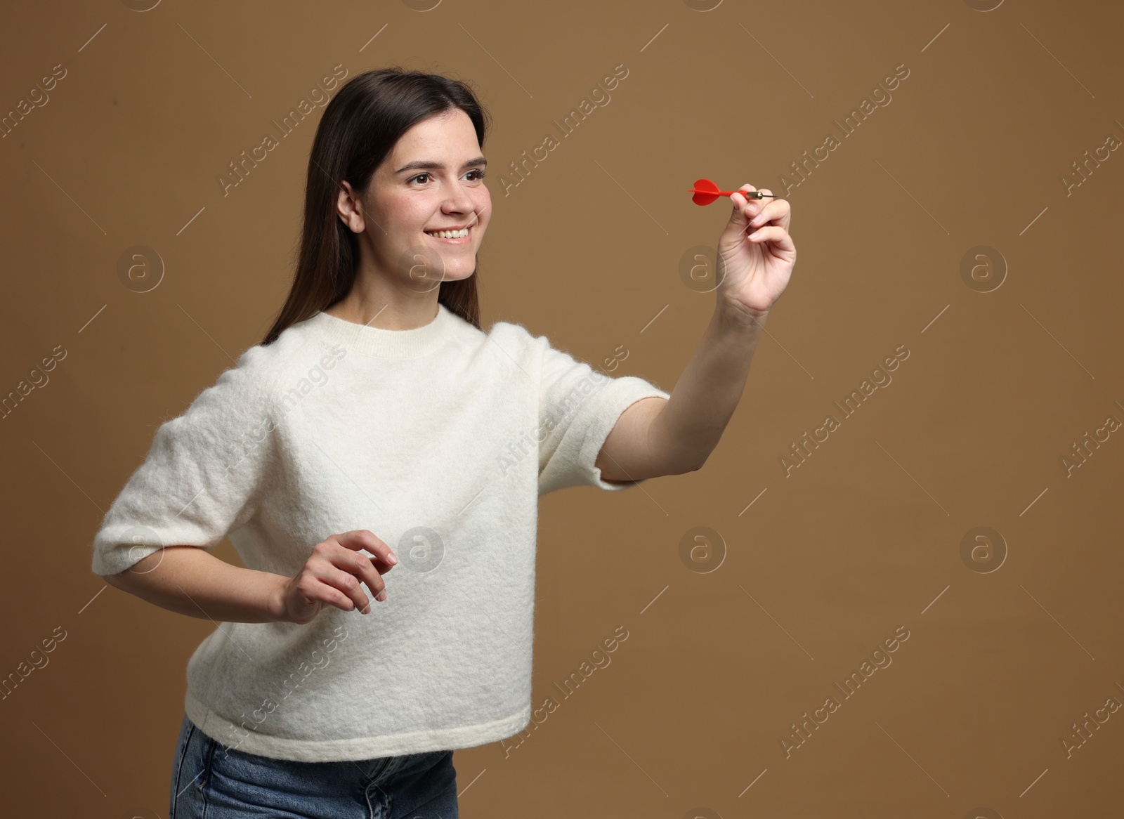 Targeting. Smiling woman with dart aiming on beige background Photo of Targeting. Smiling woman with dart aiming on beige background