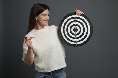 Photo of Targeting. Smiling woman with dart board and arrow on grey background