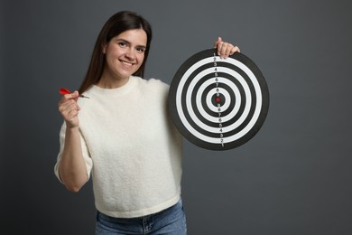 Photo of Targeting. Smiling woman with dart board and arrow on grey background