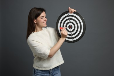 Photo of Targeting. Smiling woman with dart board and arrow on grey background