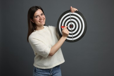 Photo of Targeting. Smiling woman with dart board and arrow on grey background